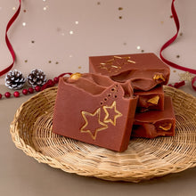 Load image into Gallery viewer, A red-brownish square soap with handpainted golden stars. The bar has a wavy top decorated with an orange slice.