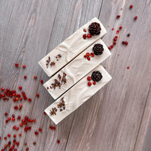Load image into Gallery viewer, Three artisan Christmas soap bars with creamy white tops decorated with mini pinecones, red berries, and natural botanicals. Vegan handmade holiday gift soap.