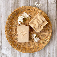 Load image into Gallery viewer, Off-white, tall soap bar with white swirls, a textured top, and a company stamp on the surface.