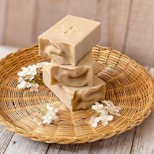 Load image into Gallery viewer, Off-white, tall soap bar with white swirls, a textured top, and a company stamp on the surface.