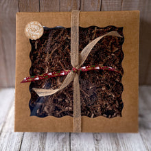 Load image into Gallery viewer, Men's Self Care Gift Basket for Dad - Natural Skincare Christmas Set: A brown kraft gift box with a clear window is filled with raffia paper and tied with brown and dark red ribbons. It features a Merry Christmas decorative sticker.