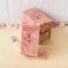 Load image into Gallery viewer, Powdery rose-colored tall soap bar with pale-rose swirls and a wavy textured top. It features a Woods and Mosses company stamp on its surface.