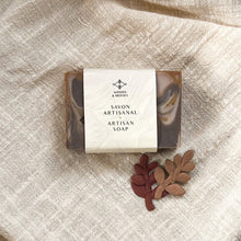 Load image into Gallery viewer, A single bar of marbled caramel and chocolate soap is wrapped in minimalist packaging that reads Woods & Mosses and Savon Artisanal - Artisan Soap.