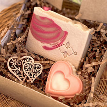 Load image into Gallery viewer, A natural soap gift box with crinkle paper, showcasing a rectangular soap with a pink swirl design and a pink heart-shaped soap. Wooden heart decorations complete the presentation, offering a handcrafted, elegant feel perfect for gifting.