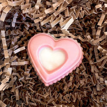 Load image into Gallery viewer, A close-up of a pink heart-shaped soap nestled in crinkle paper. The soap has a soft gradient from pink to white, creating a gentle and charming design.