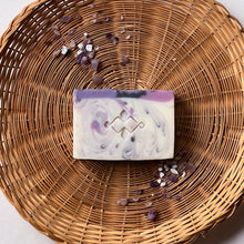 Load image into Gallery viewer, Handcrafted natural soap bar with a marbled swirl of white, lilac, and deep purple, accented with a Woods and Mosses Logo. Elegant and artistic, designed for floral scent lovers and gentle skincare.