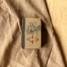Load image into Gallery viewer, Natural handmade coffee soap barwith dark textured tops and marbled tan bases, featuring an embossed Woods and Mosses logo on the side.