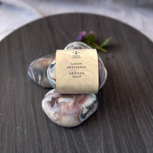 Load image into Gallery viewer, The soap bar is labeled and wrapped with recyclable paper for an eco-friendly touch. The label features the company logo and the words Artisan Soap in both French and English.