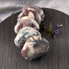 Load image into Gallery viewer, A soap bar shaped like a rock with white, brown, and dark violet swirls.