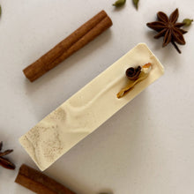 Load image into Gallery viewer, Top view of a handmade spiced orange soap bar with a smooth cream surface, decorated with a dried orange peel curl and cinnamon stick, designed for holiday gifting and seasonal skincare.