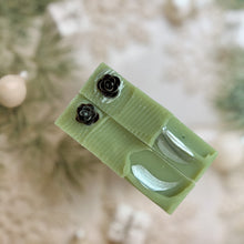 Load image into Gallery viewer, Two handpainted green holiday soap bars decorated with metallic pinecone toppers and silver crescent accents, featuring a festive artisan design inspired by Christmas and natural winter skincare.
