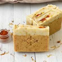 Load image into Gallery viewer, Close-up of two Calendula & Turmeric artisan soap bars on white wood background with turmeric powder and dried petals. Natural handmade skincare duo by Woods and Mosses