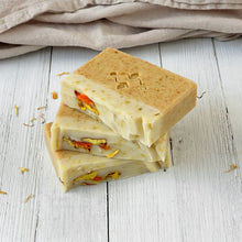 Load image into Gallery viewer, Three Calendula & Turmeric soap bars stacked diagonally, showing clean layers and flower details. Handmade bar soap with turmeric and calendula.