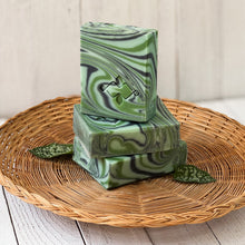 Load image into Gallery viewer, Three herbal swirl soap bars stacked and angled, each with vibrant green and white marbled design and clear Woods and Mosses embossed logo.