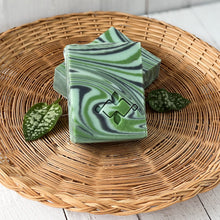 Load image into Gallery viewer, Two artisan soap bars with rich sage green swirls and visible curved edges, showcasing texture and uniform shape.