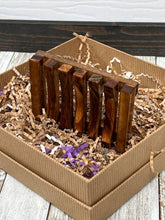 Load image into Gallery viewer, Hand‑finished wooden soap tray standing upright in gift box, surrounded by kraft and purple crinkle paper.