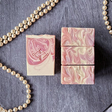 Load image into Gallery viewer, Flat lay of pink swirl artisan soap bars on a slate tray with pearls, showing top and side views. Artisan soap by Woods & Mosses.