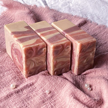 Load image into Gallery viewer, Three pink swirl soaps upright on soft fabric with pearls, showcasing marbled sides.