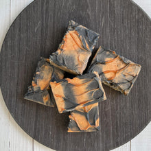 Load image into Gallery viewer, A stack of handcrafted Autumn Ember Artisan Soap bars with swirled black and orange designs, arranged on a round dark wood tray. - vegan, handmade, moisturizing cleanser, eco-friendly gift idea