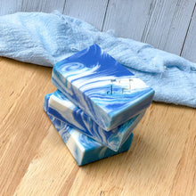 Load image into Gallery viewer, Ocean Wave soap bar styled with a natural linen cloth and wooden background, emphasizing the swirling design.