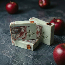 Load image into Gallery viewer, Three apple shea butter artisan soap bars arranged together, showing marbled sides and dried apple garnish.
