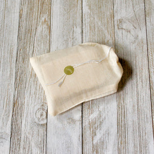 Ivory-colored muslin bag with drawstrings, reusable.