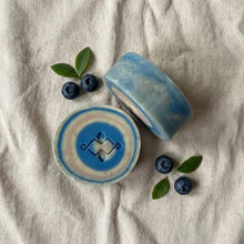 Charger l'image dans la galerie, Two round soaps with blue layered rings, one showing the stamped design and one displaying the thick side profile.
