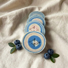 Charger l'image dans la galerie, Stack of round blue and cream swirl soaps arranged to show the carved geometric center and layered ring pattern.