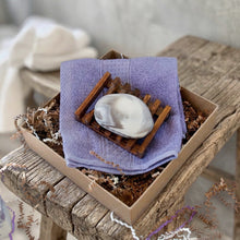 Load image into Gallery viewer, Artisan soap bar mimicking the appearance of a rock, featuring a smooth white surface accented by vibrant purple swirls that emulate natural stone patterns. Placed on wooden soap dish and purple cotton towel.
