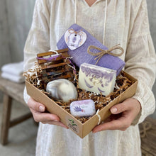 Load image into Gallery viewer, Person holding a gift box with lavender-themed items including soap and towels.