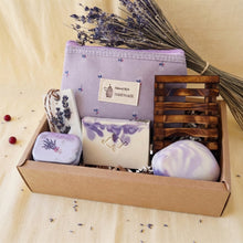 Load image into Gallery viewer, Light purple and white soap bars in a kraft box, alongside a light purple makeup bag, a purple tin, a brown wooden dish and a white wax sachet.