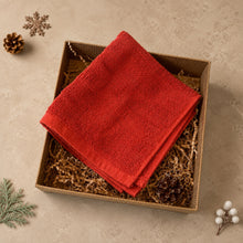 Load image into Gallery viewer, Folded red cotton face cloth in a kraft gift box with paper filler and simple Christmas decorations.