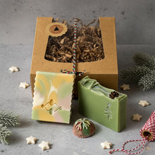 Load image into Gallery viewer, Festive artisan soaps in green and pastel shades beside a kraft box with christmas packaging.