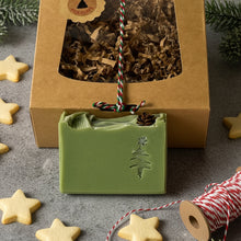 Load image into Gallery viewer, Green christmas tree soap bar with pinecone detail in front of kraft gift box.