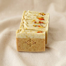 Load image into Gallery viewer, Calendula turmeric soap bars showing creamy tops, carved Woods and Mosses logo, and dried floral petals