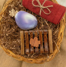 Charger l'image dans la galerie, Purple rock-shaped oval soap along with brick red cotton towel, brown wooden soap dish with seven bars, and a tiny orange leaf-shaped soap.