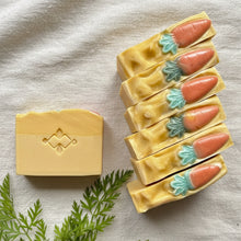 Load image into Gallery viewer, One bar of soap with carrot-shaped decorative elements  and six bars arranged in a neat row with raised vegetable design