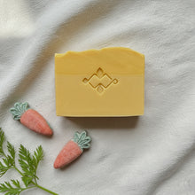 Load image into Gallery viewer, Single handmade carrot soap bar with carved stamp and two loose carrot soap pieces