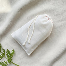 Load image into Gallery viewer, White cotton drawstring pouch holding a hidden artisan carrot soap bar