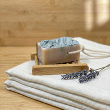 Charger l'image dans la galerie, Soap on a rope lying on a soap dish showing thick bar size, coconut oil and shea butter formula.