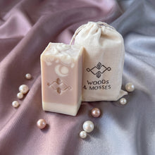 Load image into Gallery viewer, Pink and cream collagen soap bar with embossed logo beside Woods and Mosses branded cotton gift pouch.