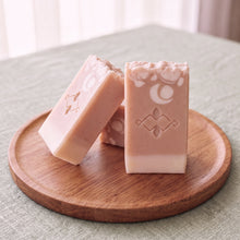 Load image into Gallery viewer, Three collagen soap bars in soft salmon tones, with cream base, white floral pattern, stamped Woods and Mosses logo, and textured tops
