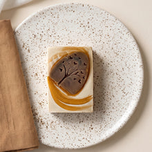 Load image into Gallery viewer, Autumn artisan soap with cream base, golden-brown swirls, and raised tree design with small heart cutouts.