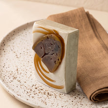 Load image into Gallery viewer, Upright Fall Vibes soap bar with cream and ochre swirls and a raised brown tree motif on a speckled plate.