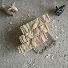 Charger l'image dans la galerie, Top view of three handmade goat milk and oatmeal soap bars with creamy marbled swirl tops.