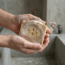 Charger l'image dans la galerie, Hands holding a lathered goat milk and oatmeal soap bar with a creamy foamy surface.