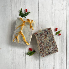 Load image into Gallery viewer, Two rectangular holiday artisan soaps, one with a frosted white surface and golden branch accents, the other with a speckled natural texture of botanicals, creating a festive Christmas gift bar with a winter woodland look