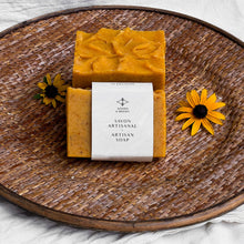 Load image into Gallery viewer, The soap bar is labeled and wrapped with recyclable paper for an eco-friendly touch. The label features the Woods and Mosses company logo and the words Artisan Soap in both French and English.