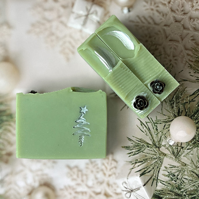 A pale green square soap with a handpainted silver Christmas tree. The bar has a wavy top decorated with a pinecone.