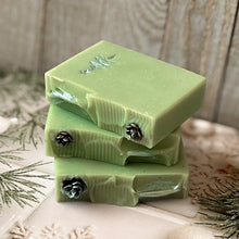 Load image into Gallery viewer, A pale green square soap with a handpainted silver Christmas tree. The bar has a wavy top decorated with a pinecone.